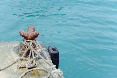 High angle view of rope tied on bollard at harbor