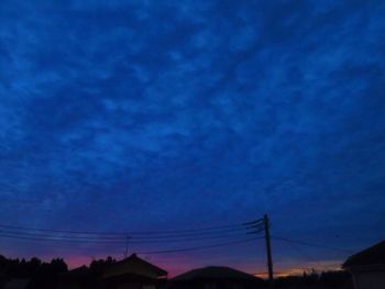 Low angle view of silhouette electricity pylon against sky