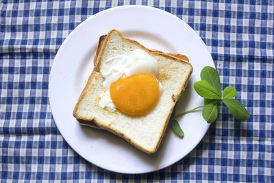 Fried egg on toast and black coffee in a glass.