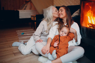 Mother kissing daughter near fireplace at hone