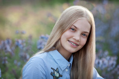 Beautiful teen girl with braces on teeth smiling. portrait of blonde model with long hair in nature 