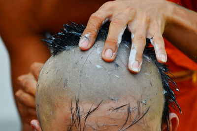 Midsection of man shaving person head