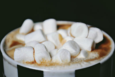 Close-up of marshmallows in coffee against black background