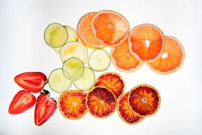 Slices of citrus cut rounds and strawberries on white background