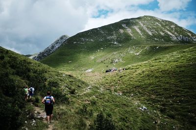 Rear view of people walking on mountain against sky