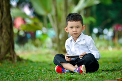 Full length of boy sitting on grass