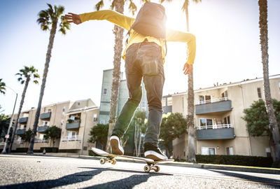 Man skateboarding on street in city against sky