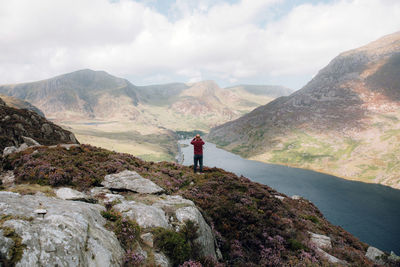 Rear view of man standing on mountain against sky