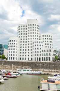 Buildings by river against sky in city