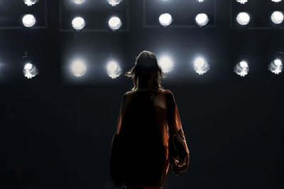 Rear view of woman standing against illuminated lights