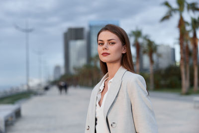 Portrait of young woman standing against sky