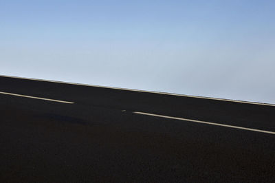 Low angle view of empty road against clear blue sky