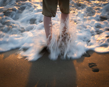 Low section of man standing on beach