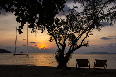 Silhouette tree by sea against sky during sunset