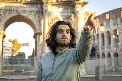 Young man traveling to rome. the man points the right direction