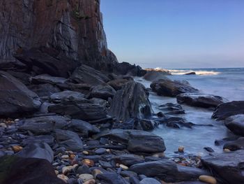 Rocks in sea against clear sky