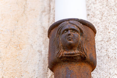 Human figure with a female face forged in the metal of a water pipe.