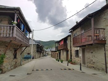 Empty road amidst buildings against sky
