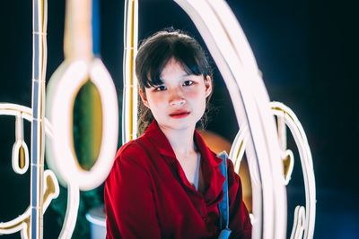 Portrait of young woman standing against mirror