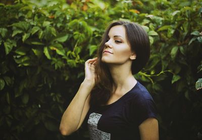 Beautiful young woman looking away against plants