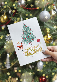 Text on hand holding christmas tree