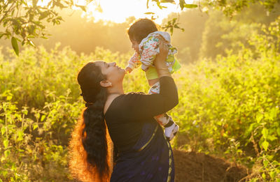 Side view of mother and daughter against plants