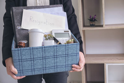 Midsection of businessman with objects standing in office