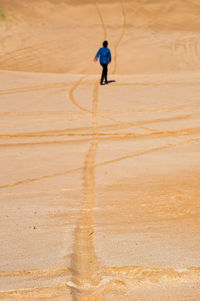 Rear view of man running on sand at beach