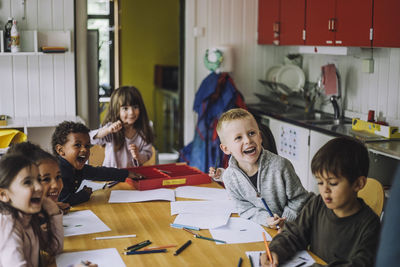 Cheerful male and female students enjoying while learning in kindergarten