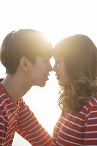 Portrait of couple kissing against clear sky