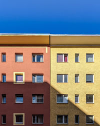 Low angle view of yellow building against clear blue sky