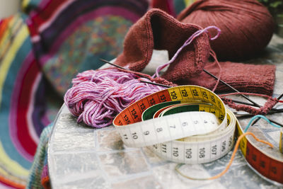 Tape measure with wool and knitting needles on table