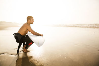 Young man on beach against sky