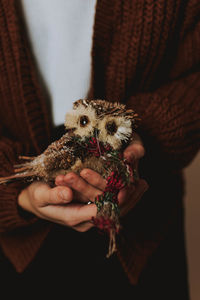 Midsection of woman holding bird decoration