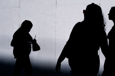 Three silhouettes of  women walking 