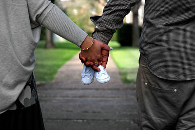 Midsection of couple with baby booties in park