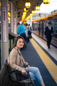 Full length of woman sitting at railroad station