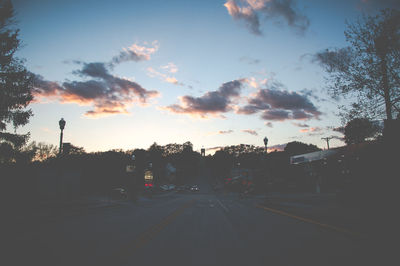 Cars on street against sky during sunset