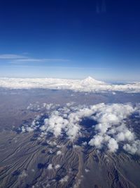 Aerial view of snowcapped mountains against blue sky