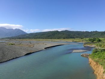 Scenic view of lake by mountains against blue sky