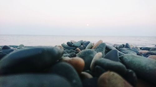 Rocks on beach against sky during sunset