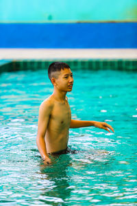 Full length of shirtless boy swimming in pool