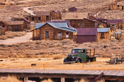 Old abandoned car on road by buildings