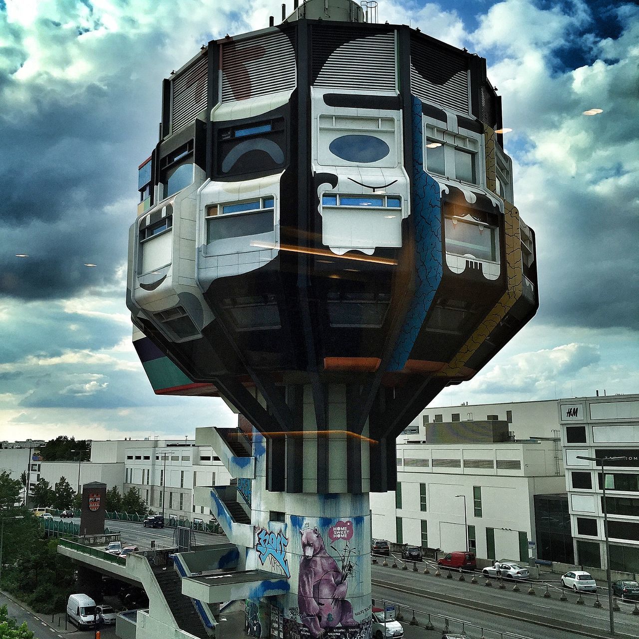 sky, building exterior, cloud - sky, architecture, built structure, cloudy, land vehicle, transportation, car, cloud, mode of transport, city, street, incidental people, day, road, outdoors, travel, city life, building