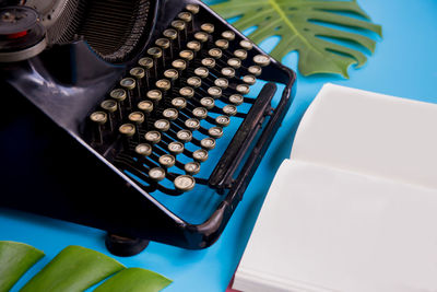 Close-up of typewriter and book against blue background