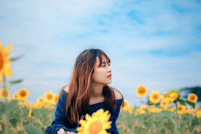 Close-up of woman with yellow flower against sky