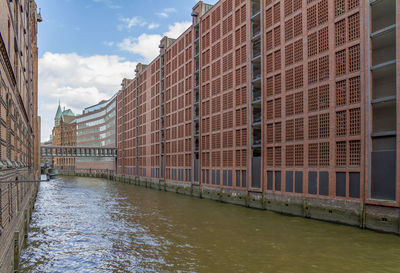 View of canal by buildings against sky