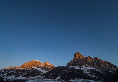 Scenic view of snowcapped mountains against clear blue sky at sunrise