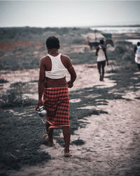 Rear view of people walking on beach