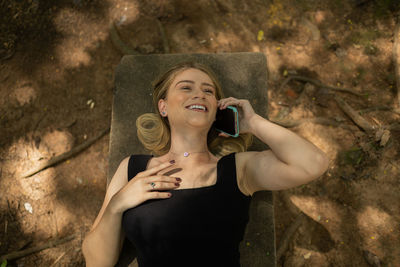 Woman using a smartphone at day time lying down on a bench at a park. mobile phone, technology, l